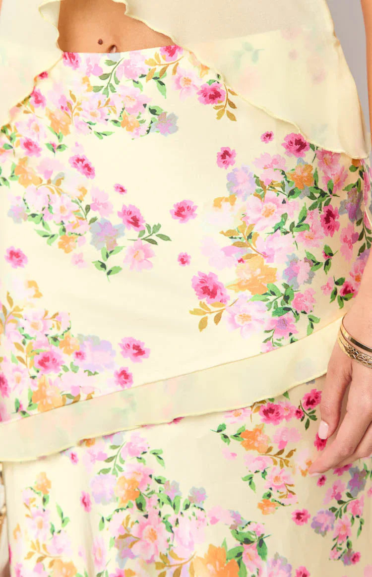 Close-up of yellow floral maxi skirt with layered ruffle detail and pastel print.