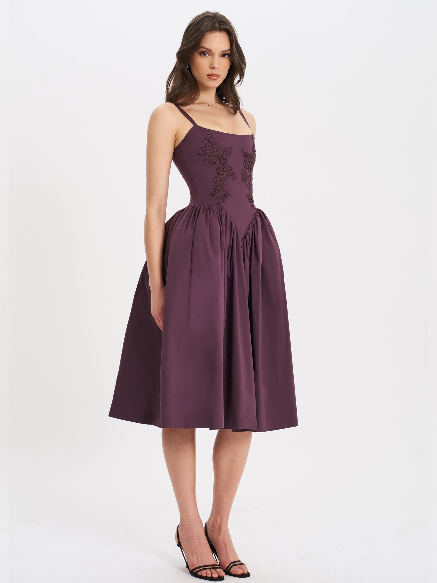 Purple lace midi dress with delicate straps, styled with black heels — side view.