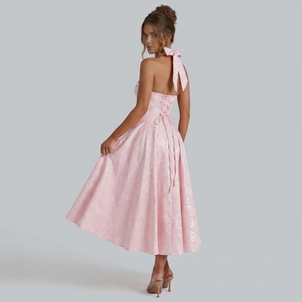 Pink jacquard halter midi dress with bow-tied back — side view focusing on the corset-style fit and sculpted waistline.
