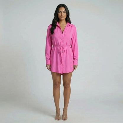 Pink tie-waist mini romper with long sleeves and mini hem — styled with heels.
