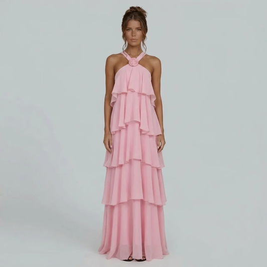 Front view of a pink ruffled halter maxi dress with a floral detail on the neckline, flowing tiered skirt.