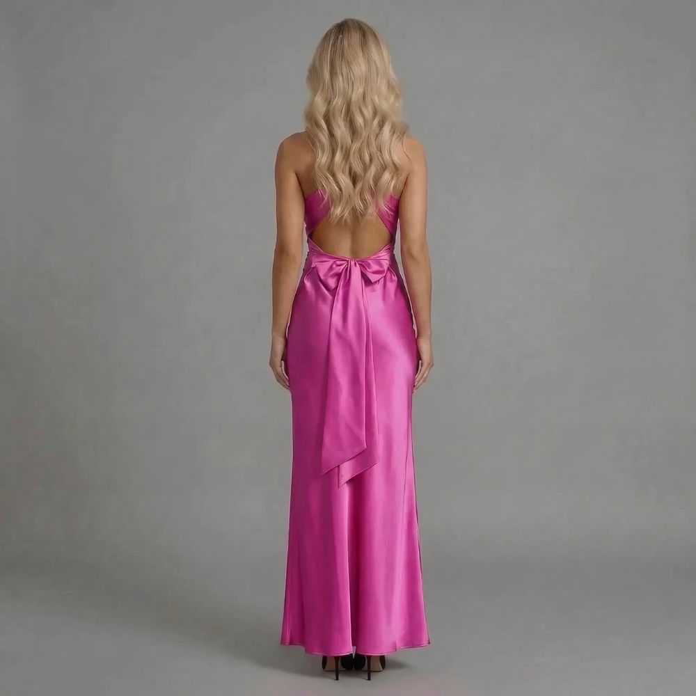 Pink twist-bust maxi dress with bow-tied open back — back view revealing dramatic bow and open back design.